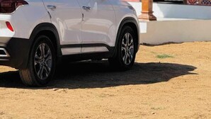Un SUV blanco estacionado frente a un edificio con techo de tejas rojas y un porche de madera.