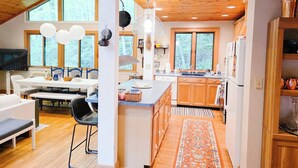 Une cuisine spacieuse avec des meubles en bois, un coin repas comprenant une table et des chaises, et de grandes fenêtres qui laissent entrer la lumière naturelle.