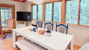 Un espace repas avec une table blanche, des chaises bleues et un plafond en bois.