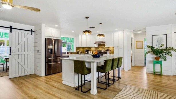 A modern kitchen with a central island, stainless steel appliances, pendant lighting, and a view of the outdoors. - 4 Br Oasis~Pool~Tiki Hut~Hot Tub~Ping Pong~Arcade (Seminole)