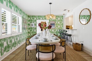 Un coin repas avec une table ronde dressée pour six personnes, entourée de chaises en osier dotées d’assises rembourrées.