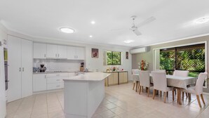 Una cocina moderna con armarios blancos, una isla central y un comedor con mesa y sillas.