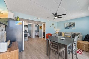 A modern kitchen with a dining area, a ceiling fan, and a view of the living room. - Seaside Serenity Unit 316 Relax & Unwind at Shore (North Wildwood)