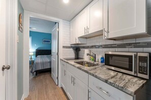 A compact kitchen with white cabinets, a microwave, and a sink.