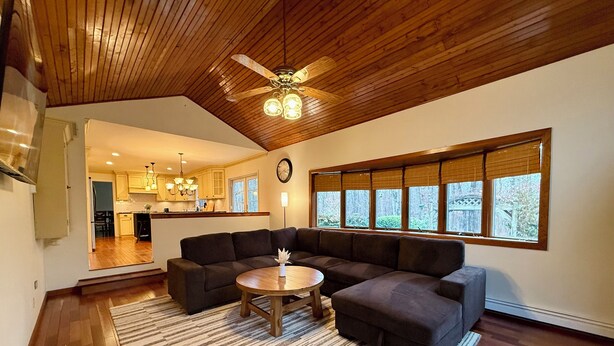 A spacious living room with a large sectional sofa, a round coffee table, and a wooden ceiling.