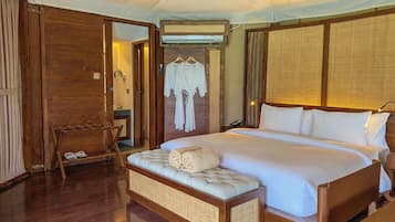 A hotel room with a bed, a wooden bench, a hanging robe, and a mirror.