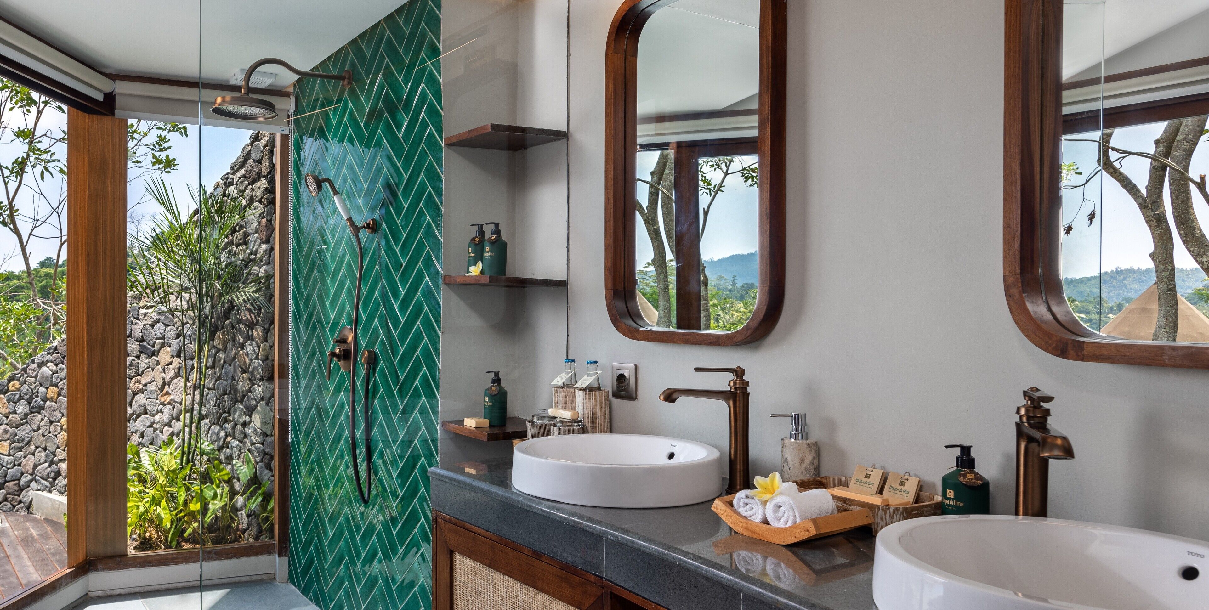 A bathroom with a large window, a shower, two sinks, and a mirror.