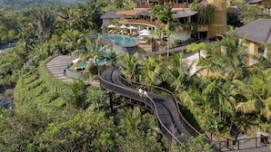A resort with a winding poolside walkway, lush greenery, and multiple buildings with outdoor seating areas. - The Wapa Lux Tent (Sidemen)