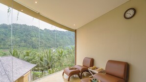 A room with a large window overlooking a lush landscape, two leather chairs, a small table, and a wall clock. - The Wapa Lux Tent (Sidemen)
