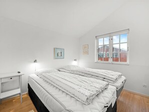 Relax in a spacious bedroom with a large bed, bedside table, and window offering a view of the surrounding area.