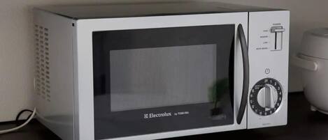 Un horno microondas con pantalla digital y panel de control, sobre una encimera negra.