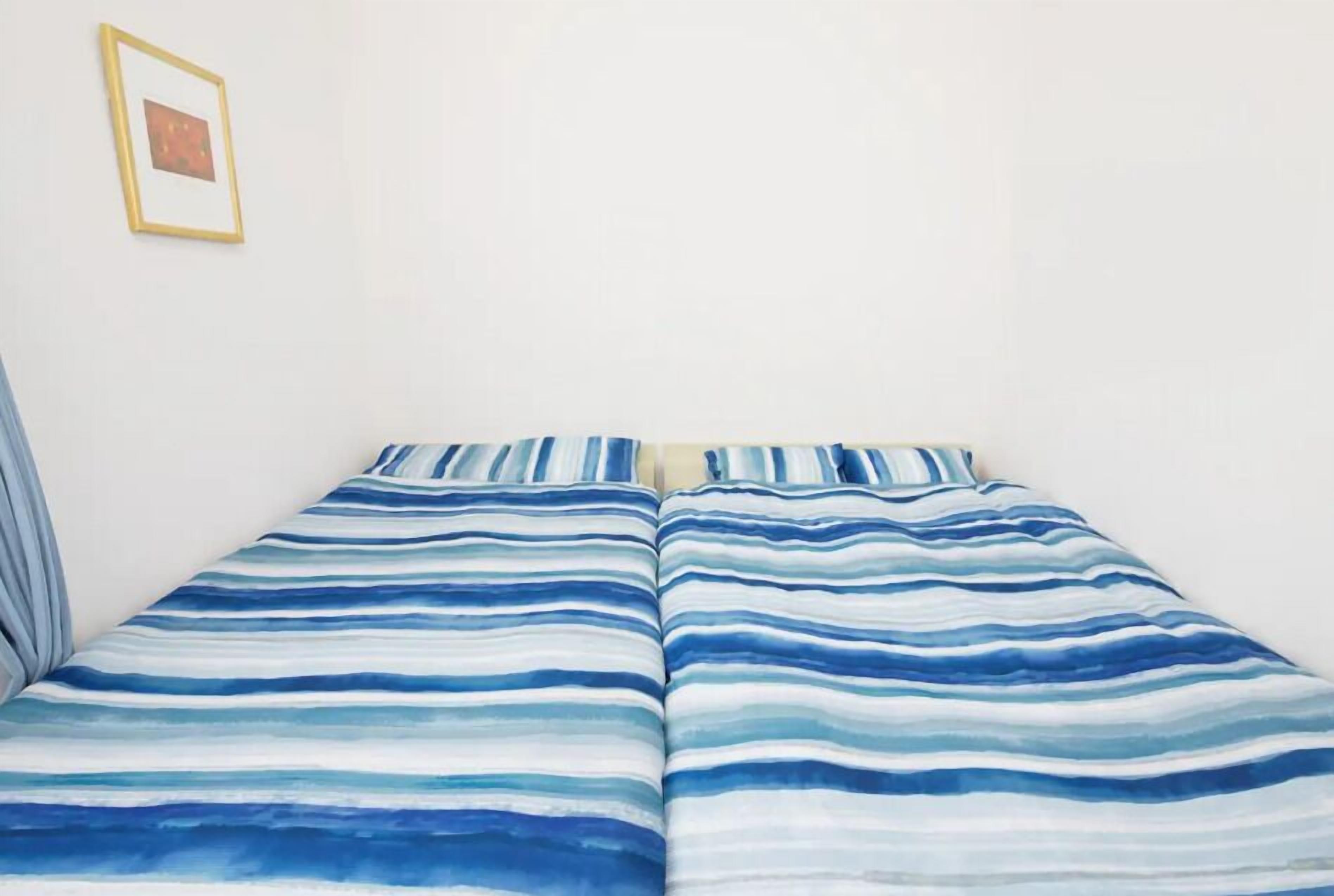 A bed with a striped blue and white bedding.