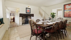 Un coin repas avec une cheminée, des chaises en bois et une table mise pour le repas.