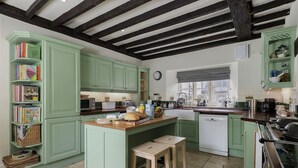 Une cuisine avec des meubles de rangement verts, un îlot central en bois et une fenêtre.