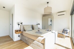A modern bedroom with a bed, bedside table, lamp, chair, and a large mirror. - Modern Sea View Villa, Private Pool, Jacuzzi & Sauna – Near Beach (Split/Trogir) (Kaštel Stari)