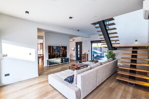 Una sala de estar moderna con un sofá grande, una mesa de centro y una escalera de madera.