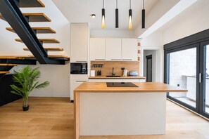 A modern kitchen with a central island, built-in appliances, and a staircase with wooden steps.