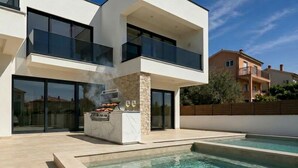 A modern two-story house with a swimming pool, a barbecue area, and a view of neighboring buildings. - Luxury Villa Heated Whirl/Pool · Sea View · AC · WIFI · Parking – Near Beach (Split/Trogir) (Kaštel Stari)