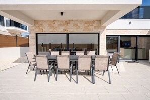 An outdoor patio with a table and chairs, a stone wall, and a modern building in the background.