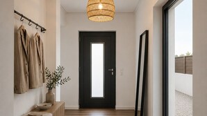 A hallway with a wooden floor, a black door, a hanging light fixture, a bench with a vase, and a coat rack with coats. - Luxury Villa Heated Whirl/Pool · Sea View · AC · WIFI · Parking – Near Beach (Split/Trogir) (Kaštel Stari)