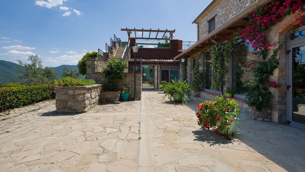 Un sendero de piedra que conduce a un edificio con una pérgola de madera y una escalera.