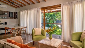 Un soggiorno moderno con soffitto in legno, un'area pranzo con tavolo e sedie, e vista su del verde all'esterno.