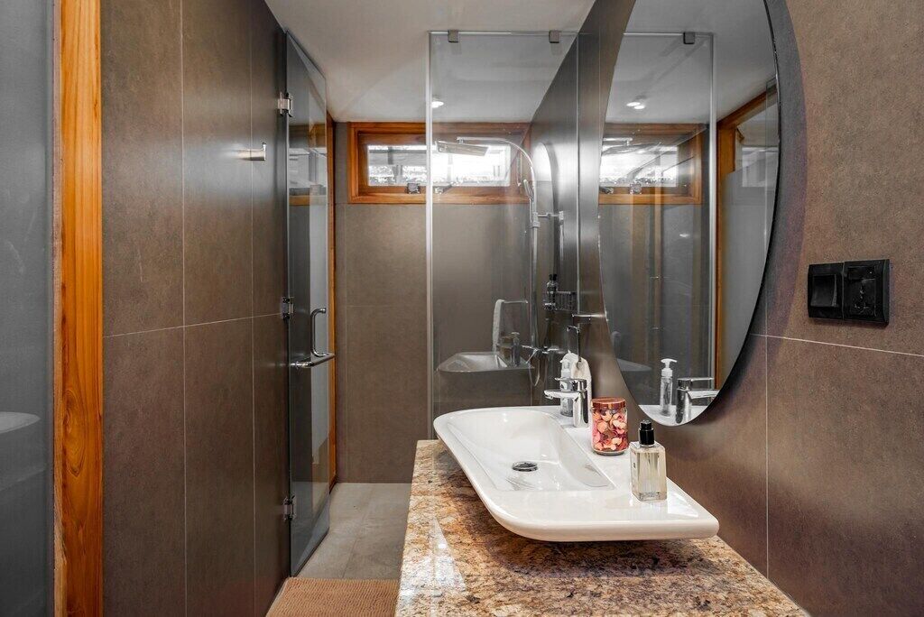 A modern bathroom with a glass-enclosed shower, a vanity with a marble countertop, and a large mirror.