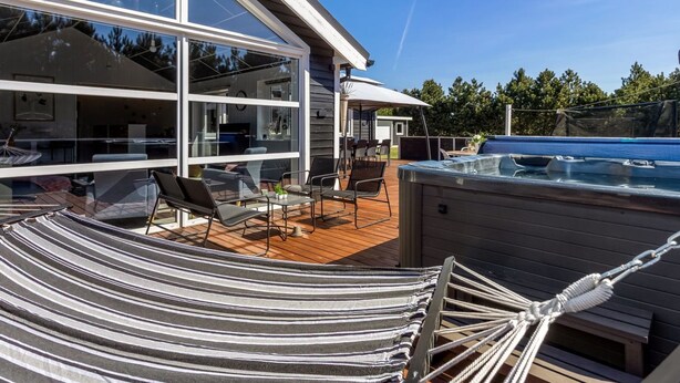 A modern outdoor deck with a hot tub, a hammock, and a dining area with outdoor furniture. - "Amdi" - 1.3km from the sea by Interhome (Væggerløse)