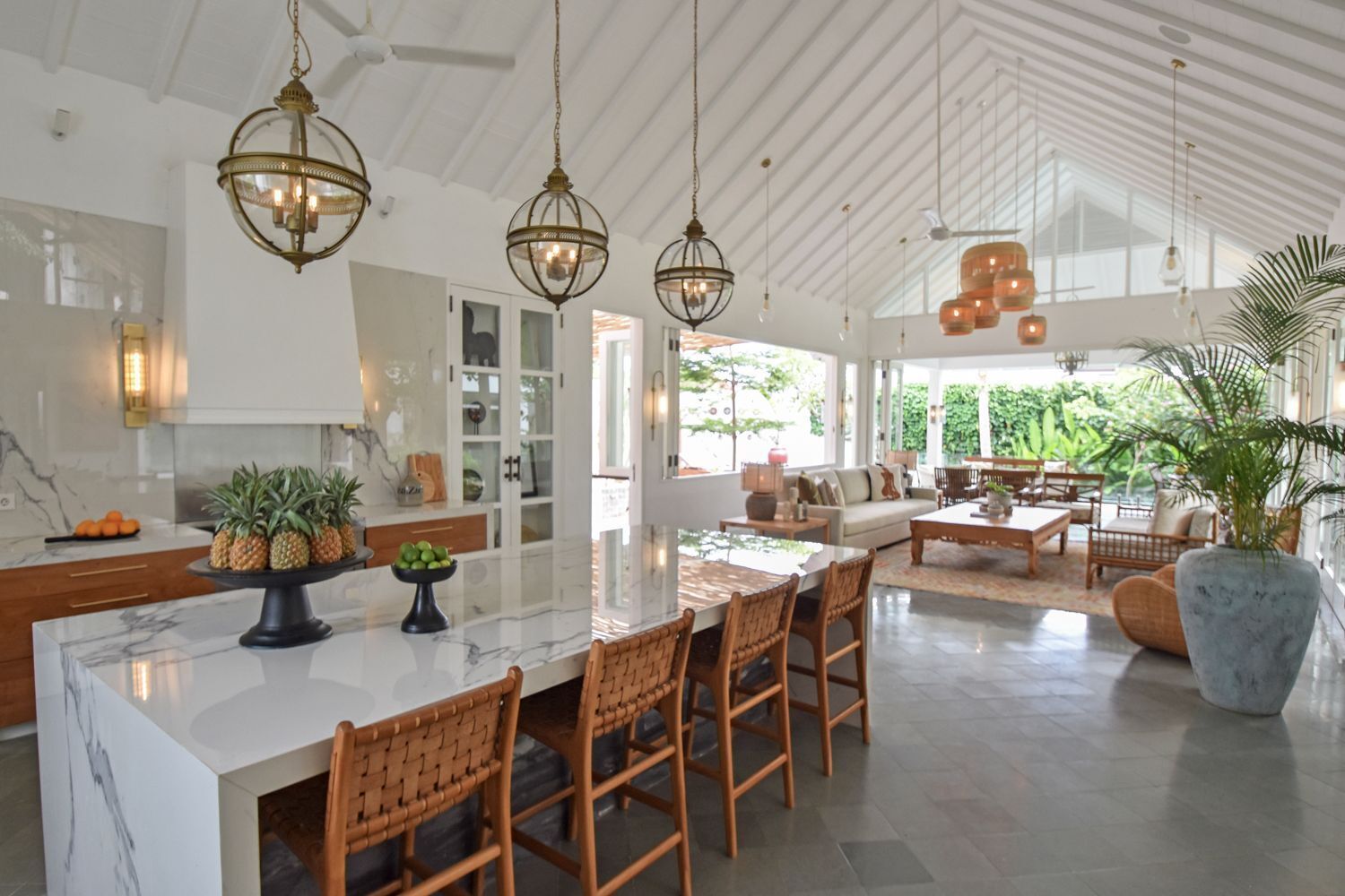 Una cocina amplia con una isla grande, sillas de madera y lámparas colgantes.
