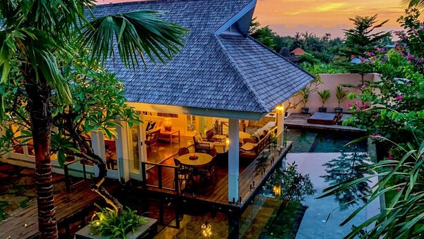 A house with a tiled roof, a pool, and outdoor seating.