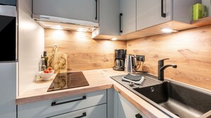 A modern kitchen with grey cabinets, a wooden countertop, a sink, and a coffee maker. - Apartment 'Inselliebe' with Balcony and Wi-Fi (Pellworm)