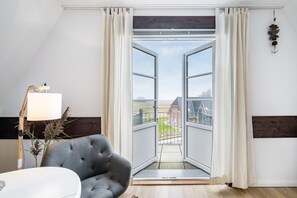 Eine offene Tür, die auf einen Balkon mit Blick auf ein Gebäude und die Landschaft führt.