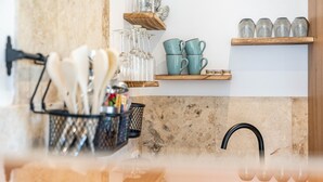 A kitchen with a marble countertop, a black faucet, a utensil holder, and shelves with glassware and ceramic mugs. - Apartment 'Am Miriquidi' with Mountain View, Shared Terrace and Wi-Fi (Marienberg)