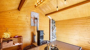 A wooden interior with a table, chairs, a fireplace, and a shelf with decorative items. - Apartment 'Am Miriquidi' with Mountain View, Shared Terrace and Wi-Fi (Marienberg)