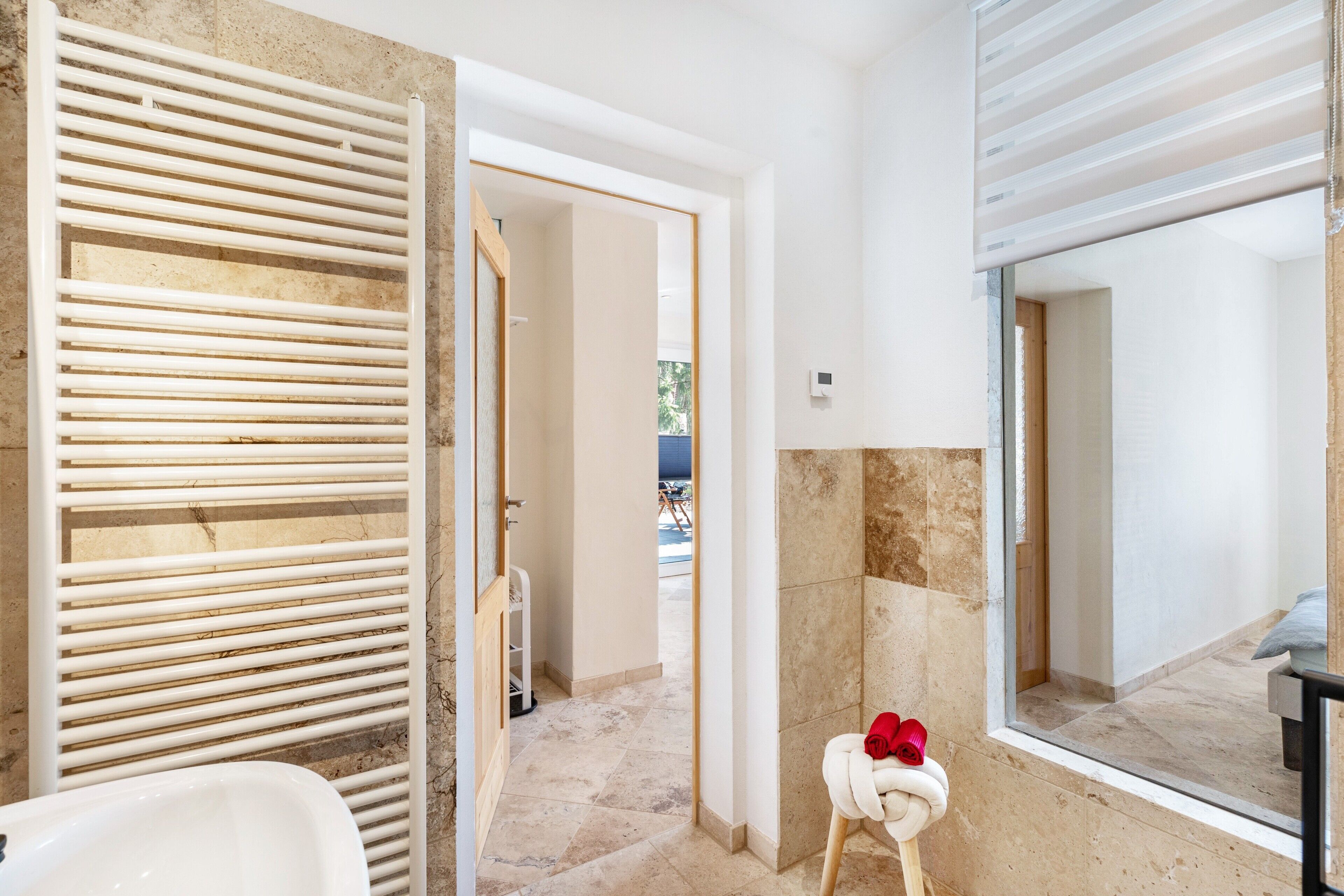 A bathroom with a white bathtub, a towel rack with a towel, and a mirror.