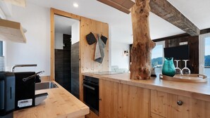 A modern kitchen with wooden cabinetry, a built-in oven, a sink, and a large wooden tree trunk centerpiece.
