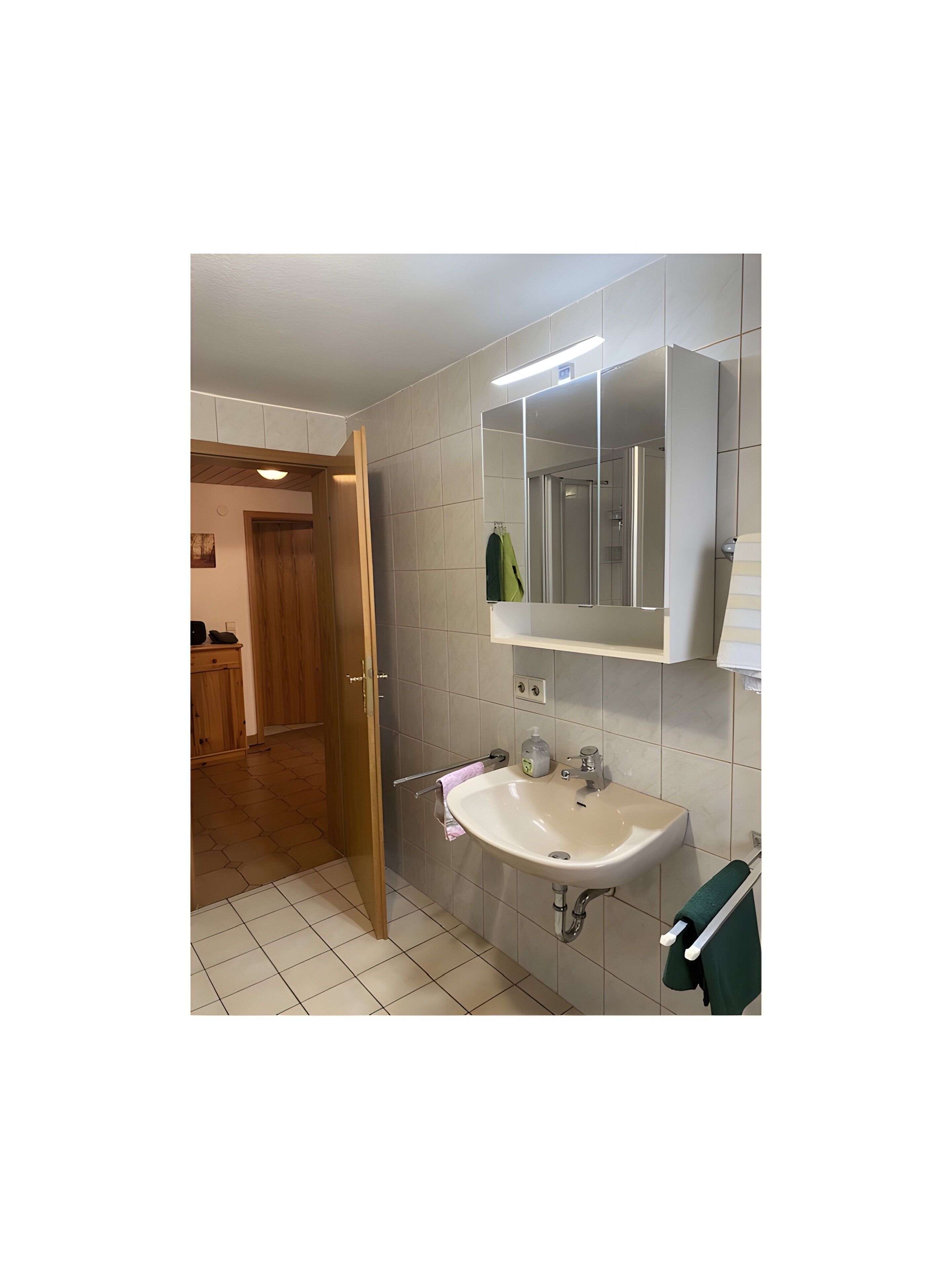 Une salle de bain avec un lavabo blanc, un miroir et un porte-serviettes.