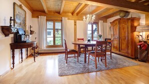Ein Essbereich mit Holzzimmermöbeln, einer Kristallleuchter und einem großen Fenster mit Vorhängen.