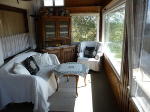 A cozy room with a wooden cabinet, a white sofa, and a chair by a window.