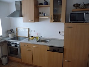 Une cuisine avec des meubles en bois, une cuisinière en acier inoxydable, un lave-vaisselle, un four à micro-ondes et une fenêtre.