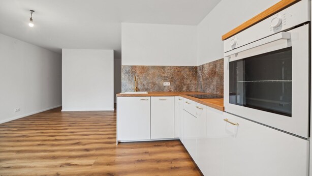 Une cuisine moderne avec des armoires blanches, un plan de travail en bois et un grand four.