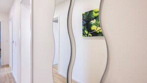 Ein Flur mit wellenförmigem Wanddesign, einem gerahmten Kunstwerk und Holzboden.