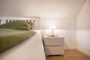 A bedroom with a bed, a nightstand with a lamp, and a white headboard. - Apartment 'At-home-in-pellworm' with Shared Garden, Balcony and Wi-Fi (Amt Pellworm)