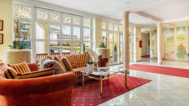 A spacious lobby with a red carpet, a sofa set, a coffee table, and large windows with a view. - Apartment 'Europa' with Shared Garden, Balcony and Wi-Fi (Bad Füssing)