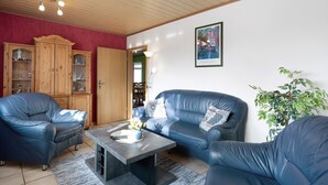 Un salon comprenant un canapé, des fauteuils, une table basse et un meuble.