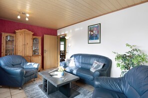 A living room with a sofa, armchairs, a coffee table, and a cabinet.