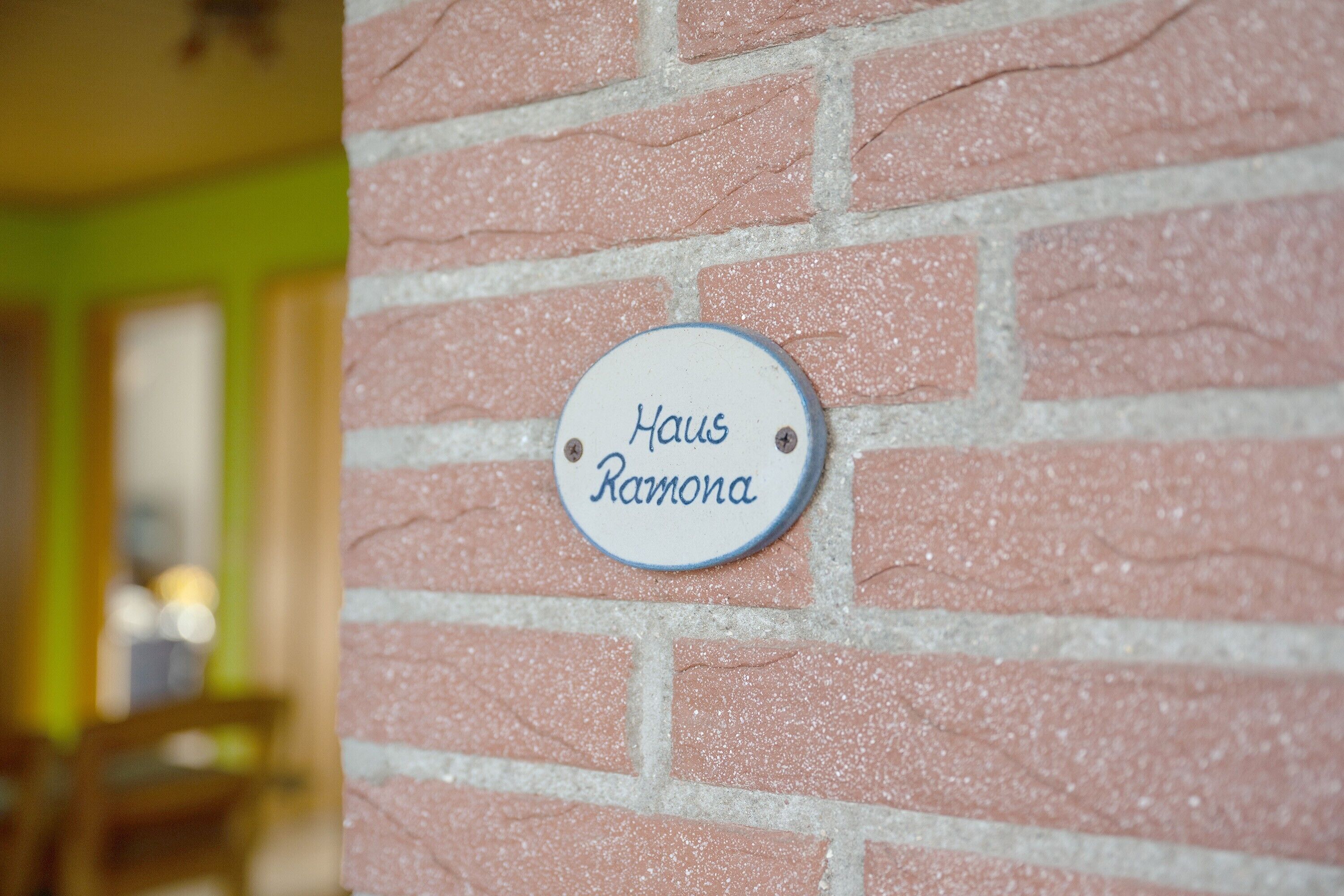 A brick wall with a plaque that reads 'Haus Ramona.'