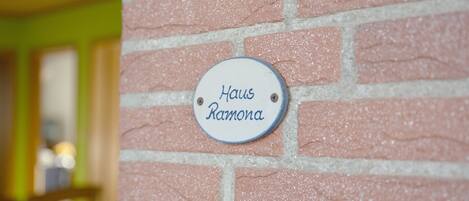 A brick wall with a plaque that reads 'Haus Ramona.'