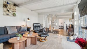 Moderni olohuone, jossa on sohva, musta nahkainen nojatuoli, puiset sohvapöydät ja koira.