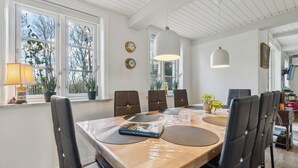 Ruokailutila, jossa on puinen pöytä, mustat tuolit, kirja ja ruukussa oleva kasvi.